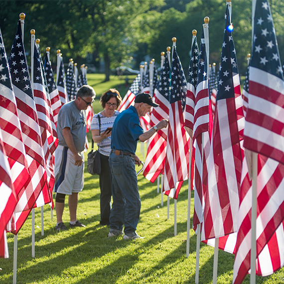Elderly Veteran and his middle-aged kids in a Healing Field of flags.