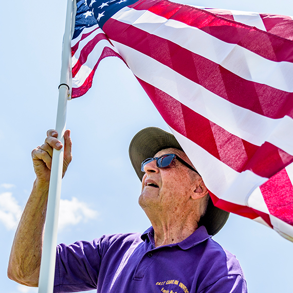 Old veteran raising a US flag.