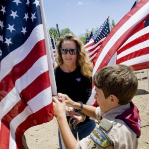 Honor scout Nic Gaita of Laguna Niguel, right, with the Order of the Arrow helps Holly Carlson-Schooley of San Juan Capistrano place a flag in honor of Navy Seal JR Schooley. The Field of Honor was organized by Homefront America for Memorial Day.

 ///ADDITIONAL INFO: 0526.sjc.honor - 5/21/16 - Photo by PAUL RODRIGUEZ - Honor scouts from the Order of the Arrow help place 300 large flags for a Field of Honor at Los Rios Park in San Juan Capistrano. The event is organized by Homefront America which will conduct a Memorial Day ceremony at the park.