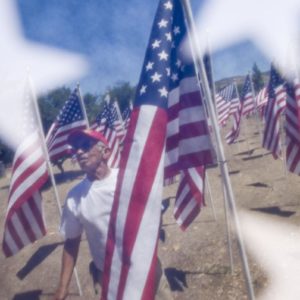 The Field of Honor can be seen through a flag as Julian Ramos of Homefront America checks flags that were placed in Los Rios Park in San Juan Capistrano for Memorial Day. Homefront America sponsored the Field of Honor.

 ///ADDITIONAL INFO: 0526.sjc.honor - 5/21/16 - Photo by PAUL RODRIGUEZ - Honor scouts from the Order of the Arrow help place 300 large flags for a Field of Honor at Los Rios Park in San Juan Capistrano. The event is organized by Homefront America which will conduct a Memorial Day ceremony at the park.