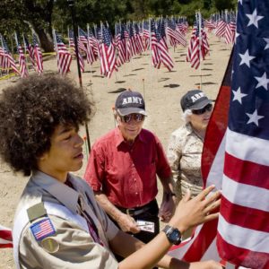 Honor scout Noah Porter, left, of the Order of the Arrow, places a flag for Julius Schnell, center, and his wife Jean, right, in the Field of Honor in Los Rios Park in San Juan Capistrano for Memorial Day. Julius and Jean, of San Juan Capistrano, met while they were both serving in the Army.

 ///ADDITIONAL INFO: 0526.sjc.honor - 5/21/16 - Photo by PAUL RODRIGUEZ - Honor scouts from the Order of the Arrow help place 300 large flags for a Field of Honor at Los Rios Park in San Juan Capistrano. The event is organized by Homefront America which will conduct a Memorial Day ceremony at the park.