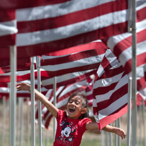 Alexia Valerio, 6, of Taos, enjoys the flag display while playing with her 9-year-old sister, Marisa Valerio, on Monday (May 28) at Taos CountyÕs 13th Annual Field of Honor in Questa.